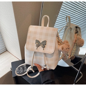 Détail du sac à dos à carreaux avec boucle papillon argentée et pendentif ourson