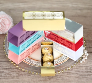 Laser-cut snowflake candy boxes in gold, purple, and silver on a wooden table