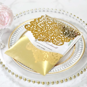 Golden laser-cut wedding invitation set with floral hollow design on marble background