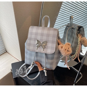 Détail du sac à dos gris à carreaux avec boucle papillon argentée et porte-clés ours