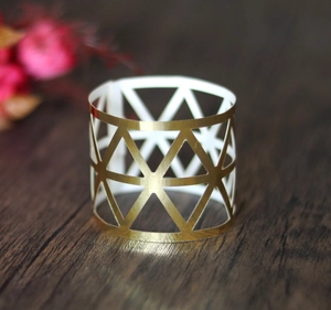Detail of laser-cut geometric gold napkin ring on rustic dark wooden table background