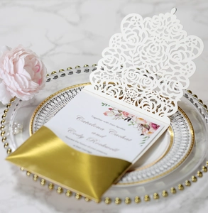 Detailed view of laser-cut rose wedding invitation with elegant gold reflective band