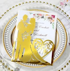Dettaglio dell'invito di nozze tagliato al laser con silhouette dorata Mr & Mrs e fiori