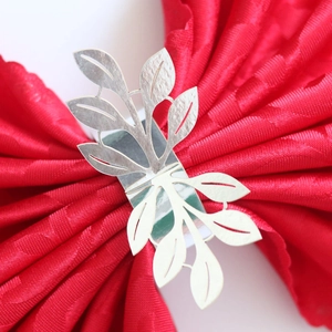 Macro shot of silver metal leaf napkin ring on a premium red textured cloth napkin