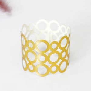Détail du rond de serviette en métal doré au design géométrique circulaire ajouré