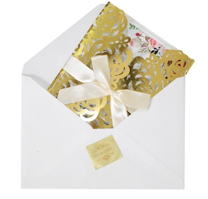 Détail d'invitation de mariage dorée découpée au laser avec enveloppe et ruban crème