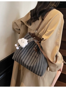 Striped canvas tote bag with brown leather straps and cloud pendant on casual trench coat
