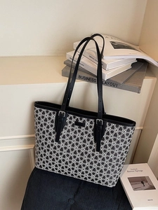 Large butterfly print tote bag with black leather handles shown on vintage books