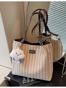 Large striped canvas tote bag with brown leather straps and a plush cloud charm accessory
