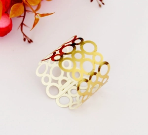Détail d'un rond de serviette doré avec structure en maille réfléchissante sur blanc