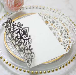 Close-up of laser-cut floral wedding invitation set on a marble surface with decor