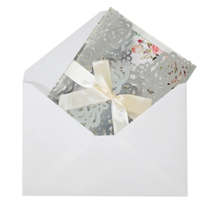 Détails d'invitations de mariage découpées au laser avec des fleurs et ruban de satin