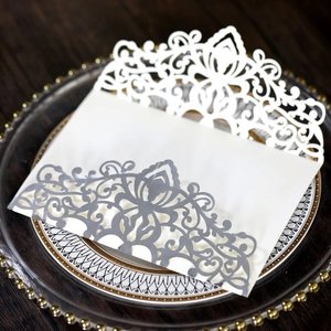 Detailed laser cut lace wedding invitation in cream and silver grey on a glass tray
