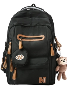 Minimalist black canvas backpack for college with brown pullers and a monkey plush keychain