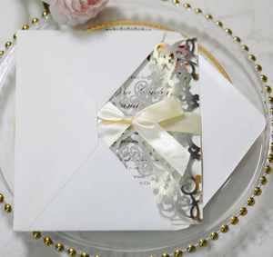 Detail view of laser-cut silver wedding invitation with cream silk ribbon and envelope