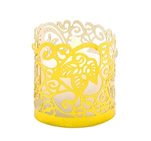 Macro detail of the bright yellow metal candle sleeve with hollow leaf and scroll patterns