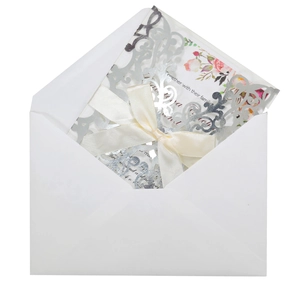 Detailed laser-cut silver wedding invitation set with ribbon bow and floral inner card