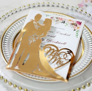 Dettaglio dell'invito di nozze oro tagliato al laser con silhouette Mr & Mrs e fiori colorati