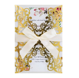 Detail of rose gold laser-cut wedding invitation with cream silk bow and floral insert
