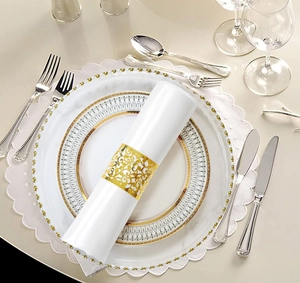 Detail einer weißen Serviette mit goldenem hohlem floralem Serviettenring auf dem Teller
