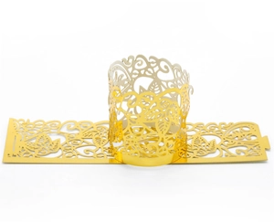 Detail of laser cut golden paper cupcake wrapper with intricate vine and leaf texture