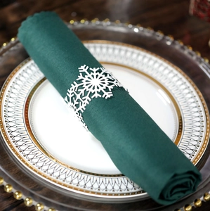Macro shot of white snowflake napkin ring on green fabric for Christmas table decor