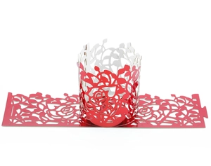 Detail of red laser-cut cupcake wrapper featuring intricate rose floral paper carving