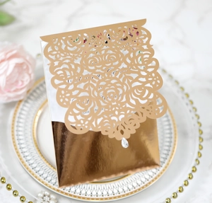 Detailed view of laser-cut rose hollow invitation with champagne gold metallic envelope
