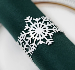 Macro shot of white snowflake napkin ring on green fabric for Christmas table setting