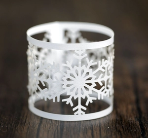 Macro shot of white laser-cut snowflake napkin ring on elegant dark wood table
