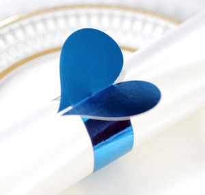 Vue rapprochée du rond de serviette en cœur bleu vif sur serviette blanche et assiette dorée