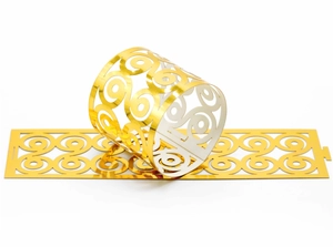 Macro detail of laser-cut hollow scrollwork on golden paper napkin rings for weddings