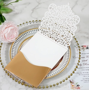 Detail of white laser-cut wedding invitation with rose hollow patterns and gold ribbon