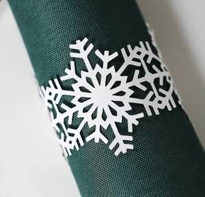 Macro detail of white snowflake napkin ring on deep green fabric for elegant dinner decor