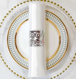 Close-up of silver hollow geometric napkin ring on a white silk napkin for party decor