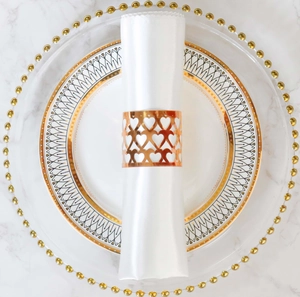 Detail of rose gold napkin ring with heart cutout design on elegant table setting
