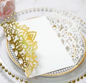 Detailed laser-cut wedding invitation sleeve in rose gold foil on a decorative plate
