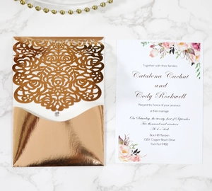Macro detail of laser-cut rose gold wedding invitation with floral hollow design