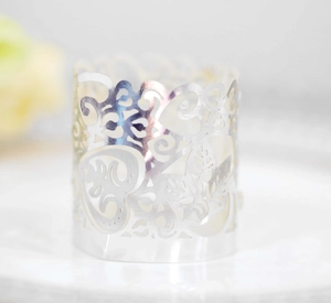 Macro detail of laser-cut silver cupcake wrapper with heart and floral leaf patterns