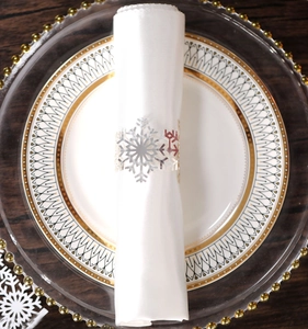 Macro detail of silver snowflake napkin ring with intricate hollow design on ceramic plate