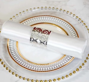 Macro shot of silver hollowed butterfly napkin ring on white silk napkin and marble table