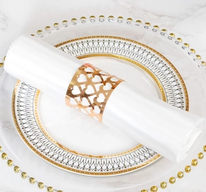 Macro detail of gold laser-cut heart pattern napkin ring on elegant white silk cloth
