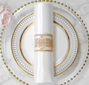 Detailed view of a laser-cut gold snowflake paper napkin ring on a white satin napkin