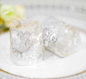 Detail of white laser-cut hollow paper candle sleeves with heart and leaf patterns