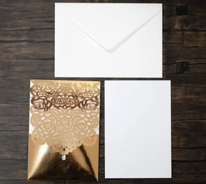 Detail of laser-cut gold wedding invitation set with envelope and teardrop gemstone