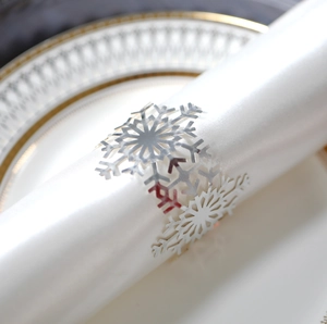 Close-up of a silver snowflake napkin ring with intricate cutouts on a white satin napkin