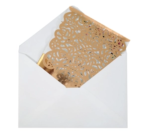 Close-up of laser-cut rose patterns on gold foil wedding invitation with white envelope