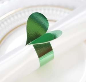 Détail d'un rond de serviette cœur vert métallique sur serviette en soie blanche chic