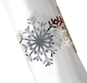 Macro detail of silver snowflake napkin ring with hollow-out design on white silk fabric