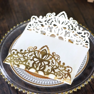 Close-up of laser-cut rose gold invitation card with floral patterns on glass tray